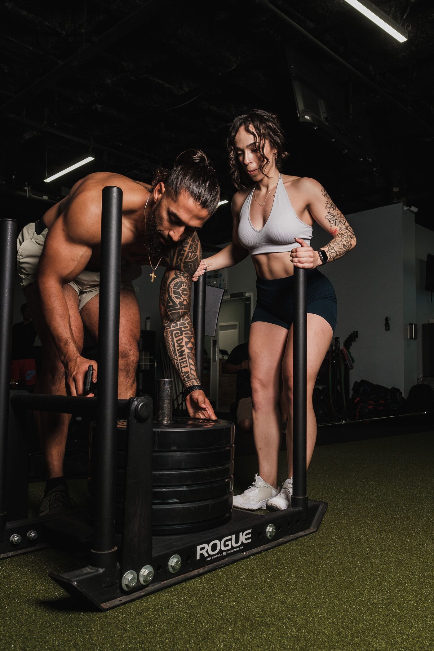 Two people preparing a weighted sled for a gym session