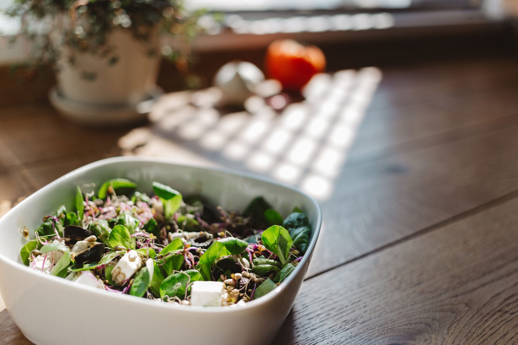 A bowl of leafy green salad on a wooden table